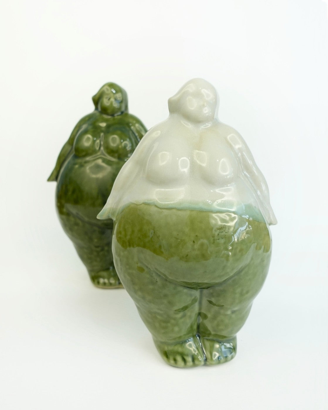Two ceramic figures, one green and one white, on a white background