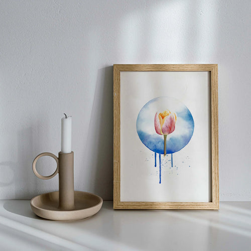 Framed artwork of a tulip with watercolor design on a white surface next to a candle holder.
